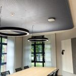 kleiner Konferenzraum mit abgehängten Lochgipsdeckensegel mit abgerundeten Ecken, in dunkelblauer Farbe getaucht